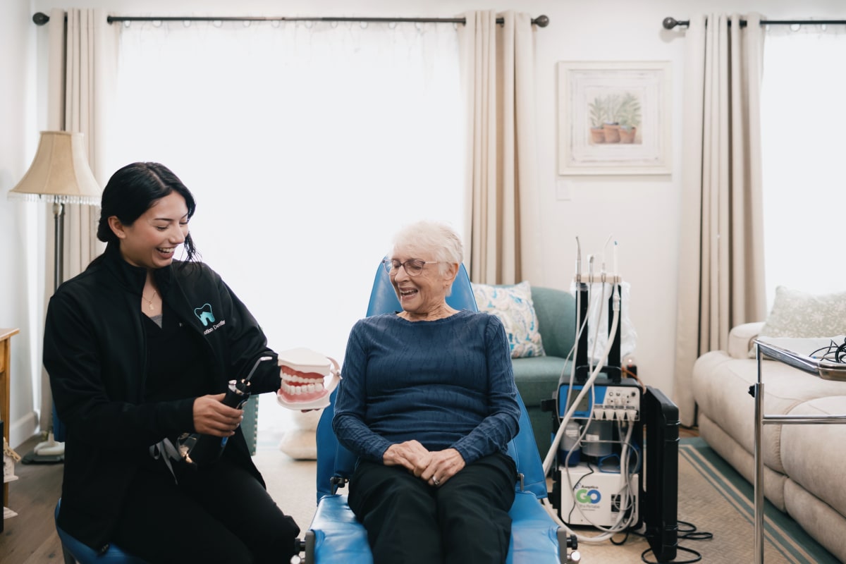 Caregiver assisting elderly patient with teeth brushing at home