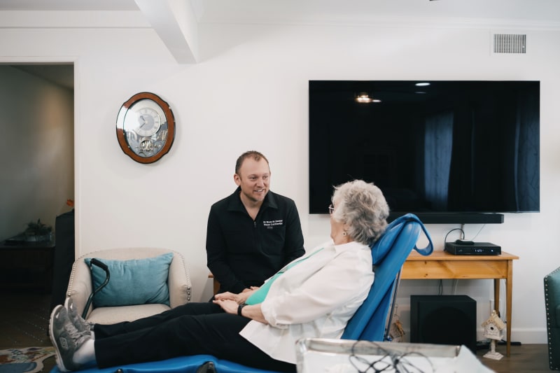 Dental professional demonstrating teeth brushing technique to elderly patient in home setting