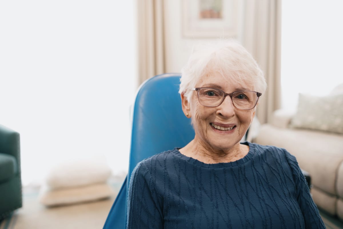 Elderly patient smiling in home setting wearing teal shirt during house call dental visit