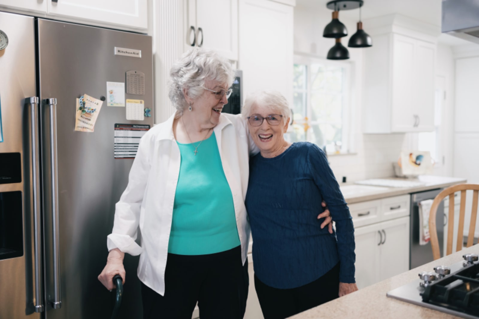 Two women in professional setting discussing insurance or paperwork at kitchen counter