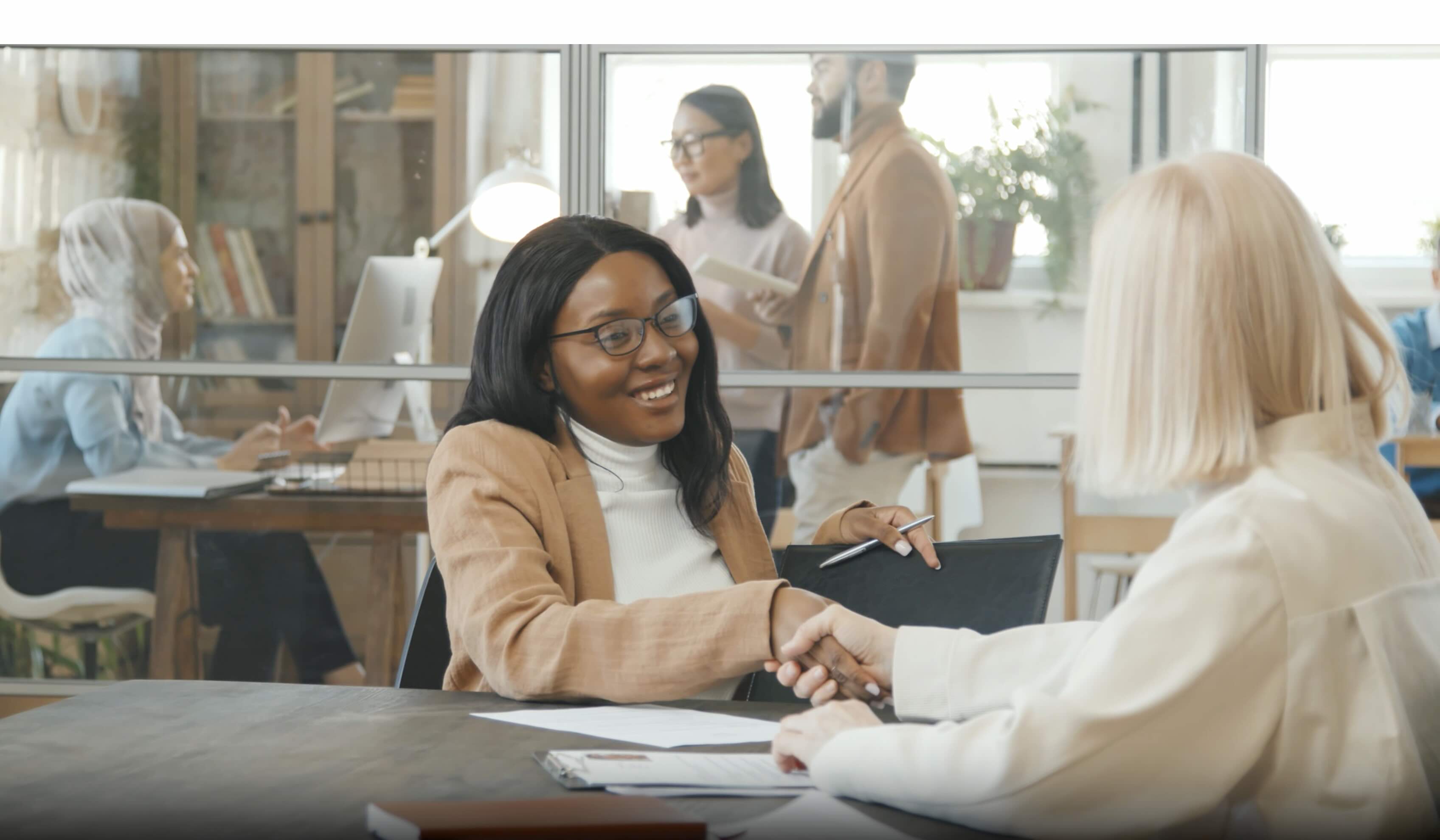 Two professionals sitting at a table shaking hands