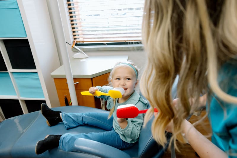 Young child in dental chair smiling, demonstrating comfortable pediatric dental experience