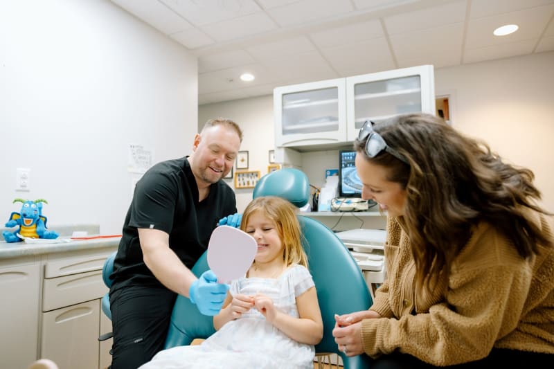 Pediatric dentist applying fluoride varnish treatment to young patient's teeth at Frederick Pediatric Dentistry in Maryland.