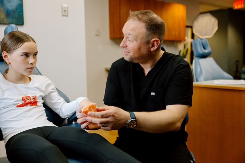 Dr. Mike showing a teenage girl a model of teeth at Frederick Pediatric Dentistry