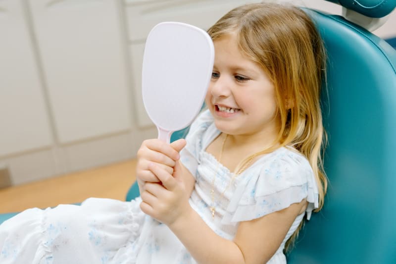 Pediatric dentist examining child's teeth during routine dental checkup for oral health