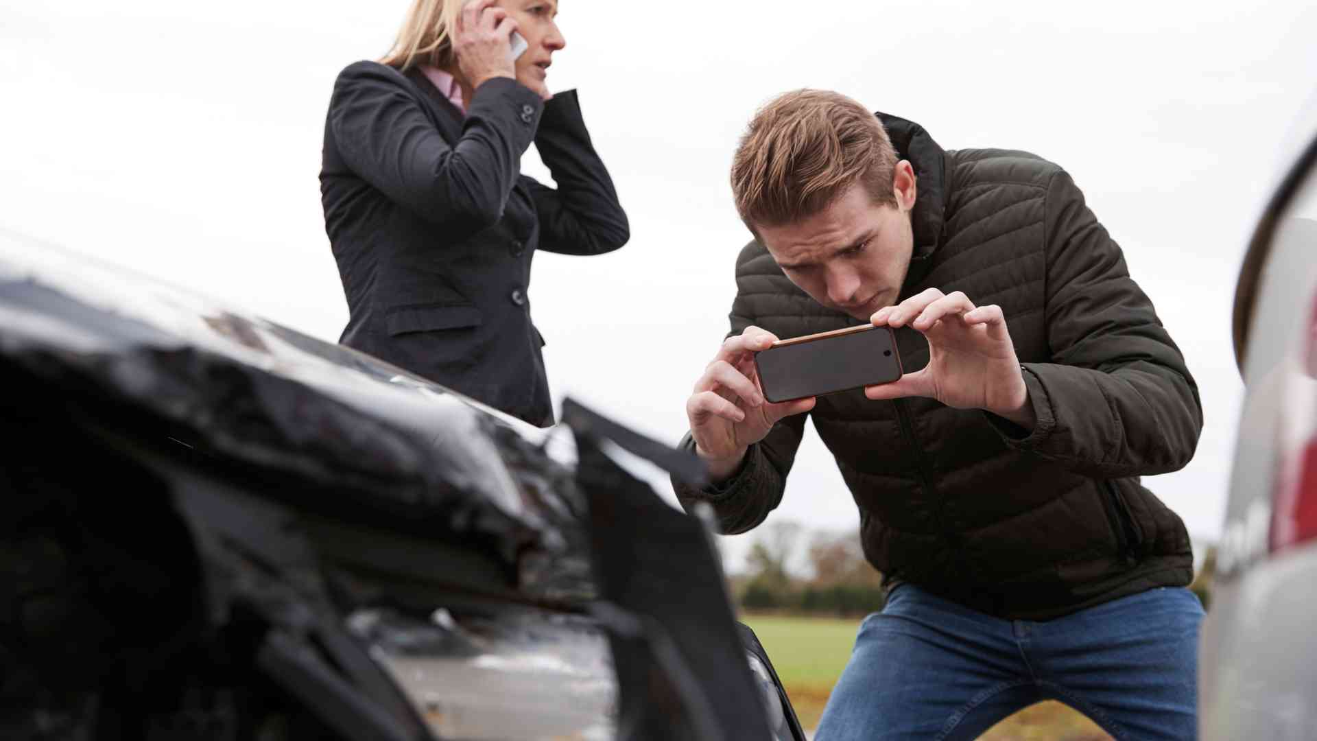 A man clicking the picture of a car after the car collision