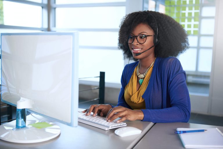 stock photo woman in glasses at desk with headset on smiling