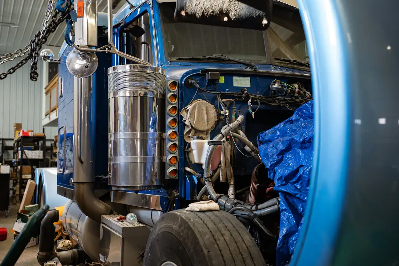 DOT inspection on a semi-truck in a repair shop with the hood open for heavy-duty maintenance.