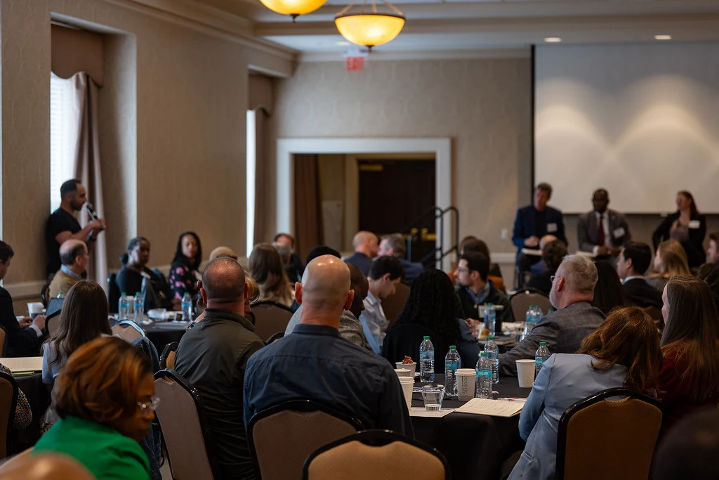 The audience looking at someone asking a question at the HEMAC annual convening.