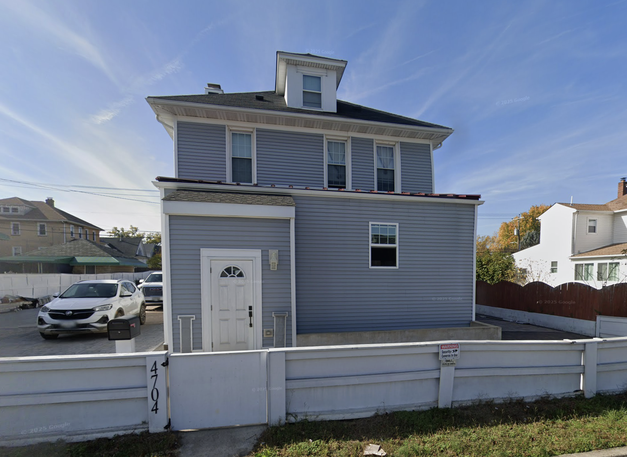 a blue house with a low, white fence that has the numbers 4704 vertically on the fence