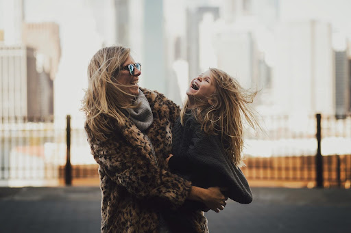 Photo of book[ed] founder Kim, holding her daughter. They are laughing and smiling.