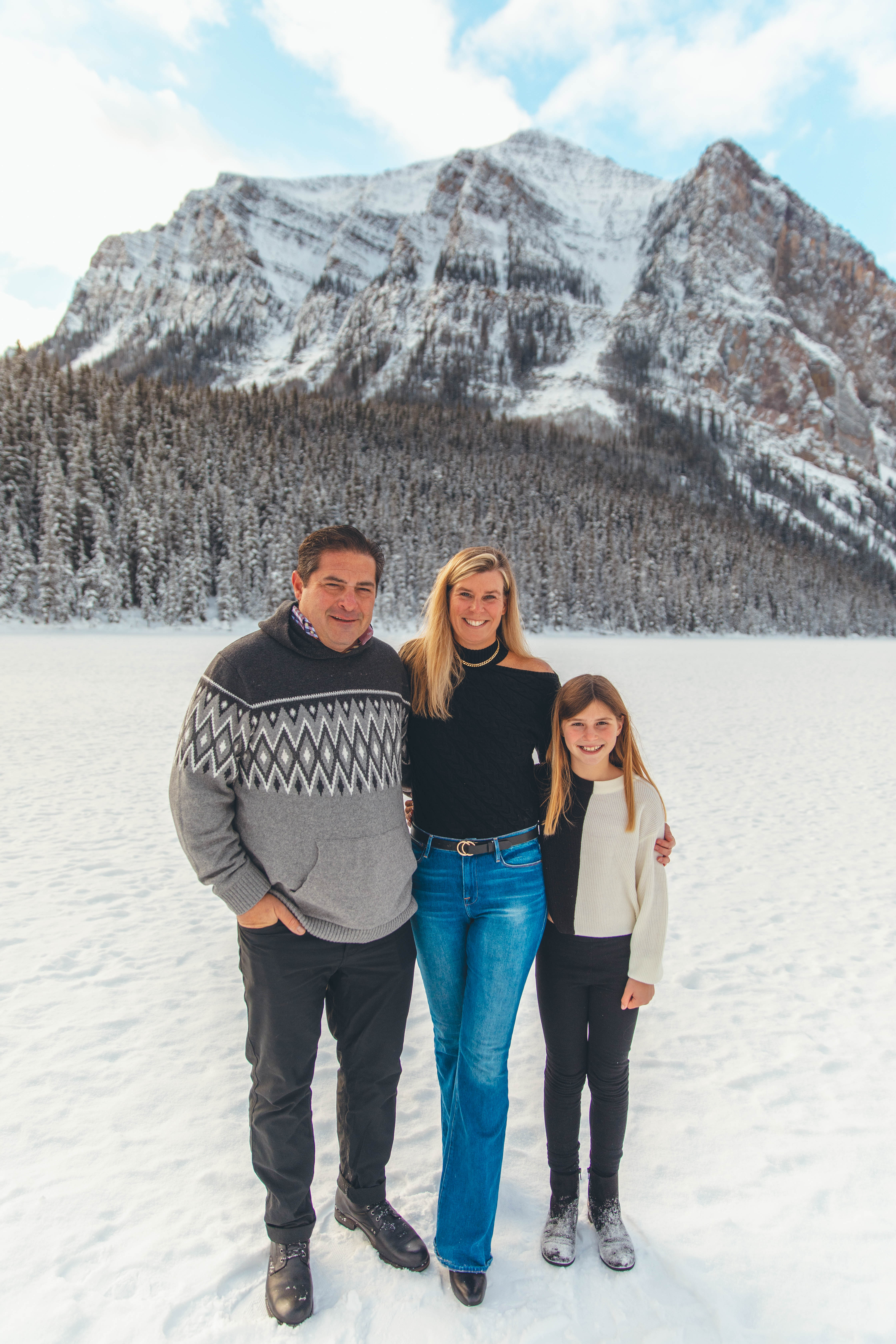 Photo of book[ed] founder Kim, posing with her husband and daughter in a snowy mountain setting.