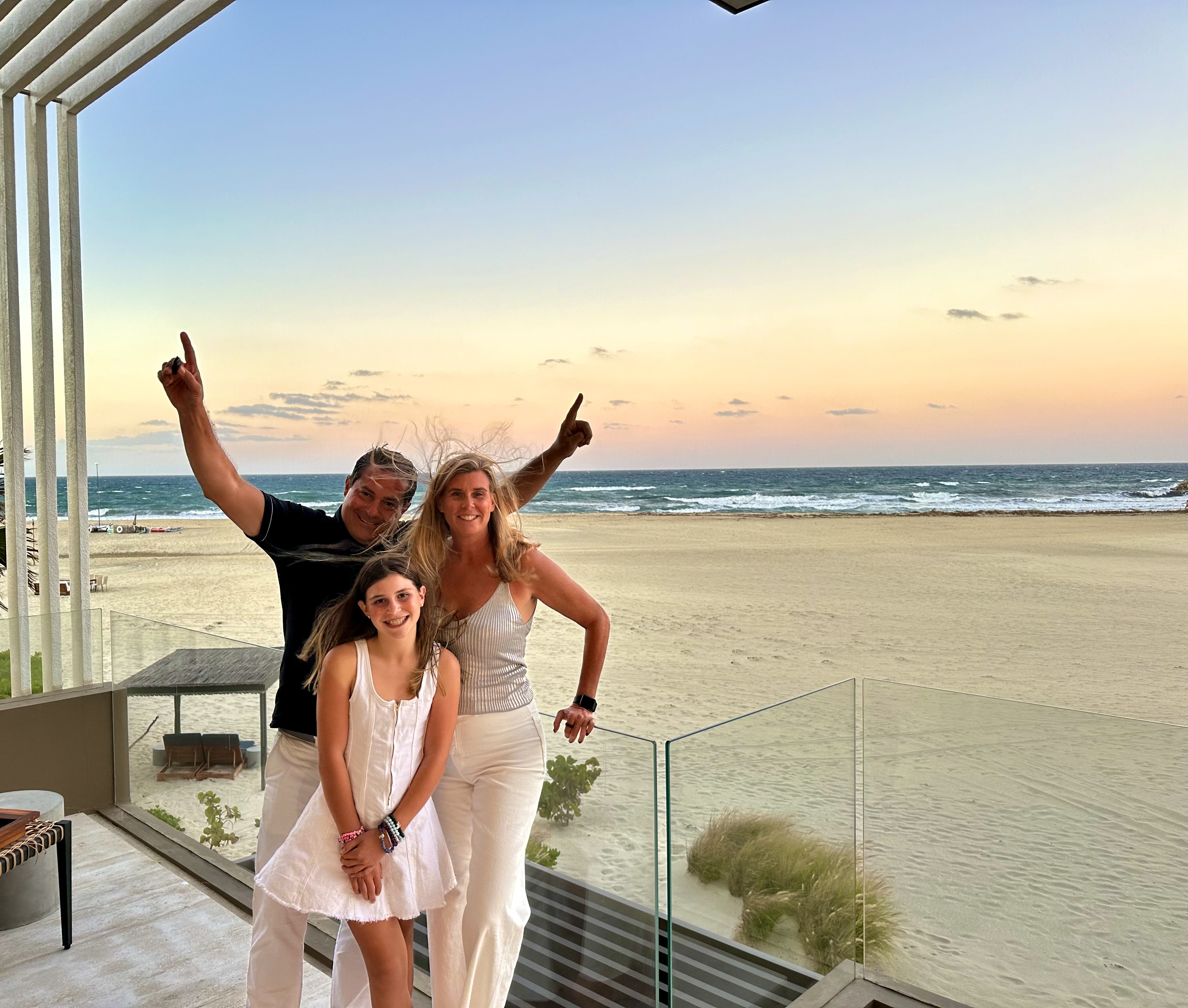 Photo of book[ed] founder Kim, posing with her husband and daughter on the beach.