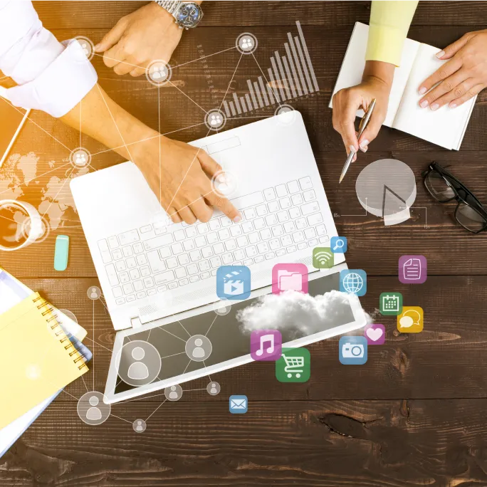 A birds-eye view of people working on a laptop. There are illustrations of app icons imposed over the image.
