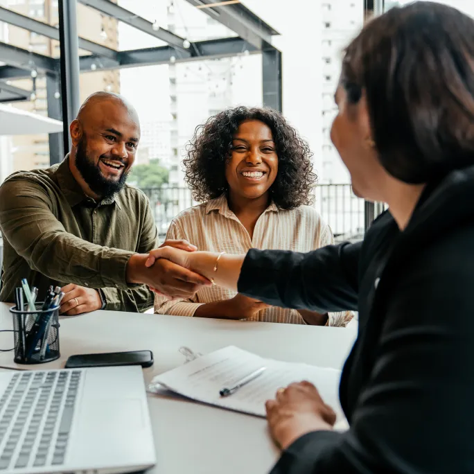 A couple meeting with an advisor and shaking hands
