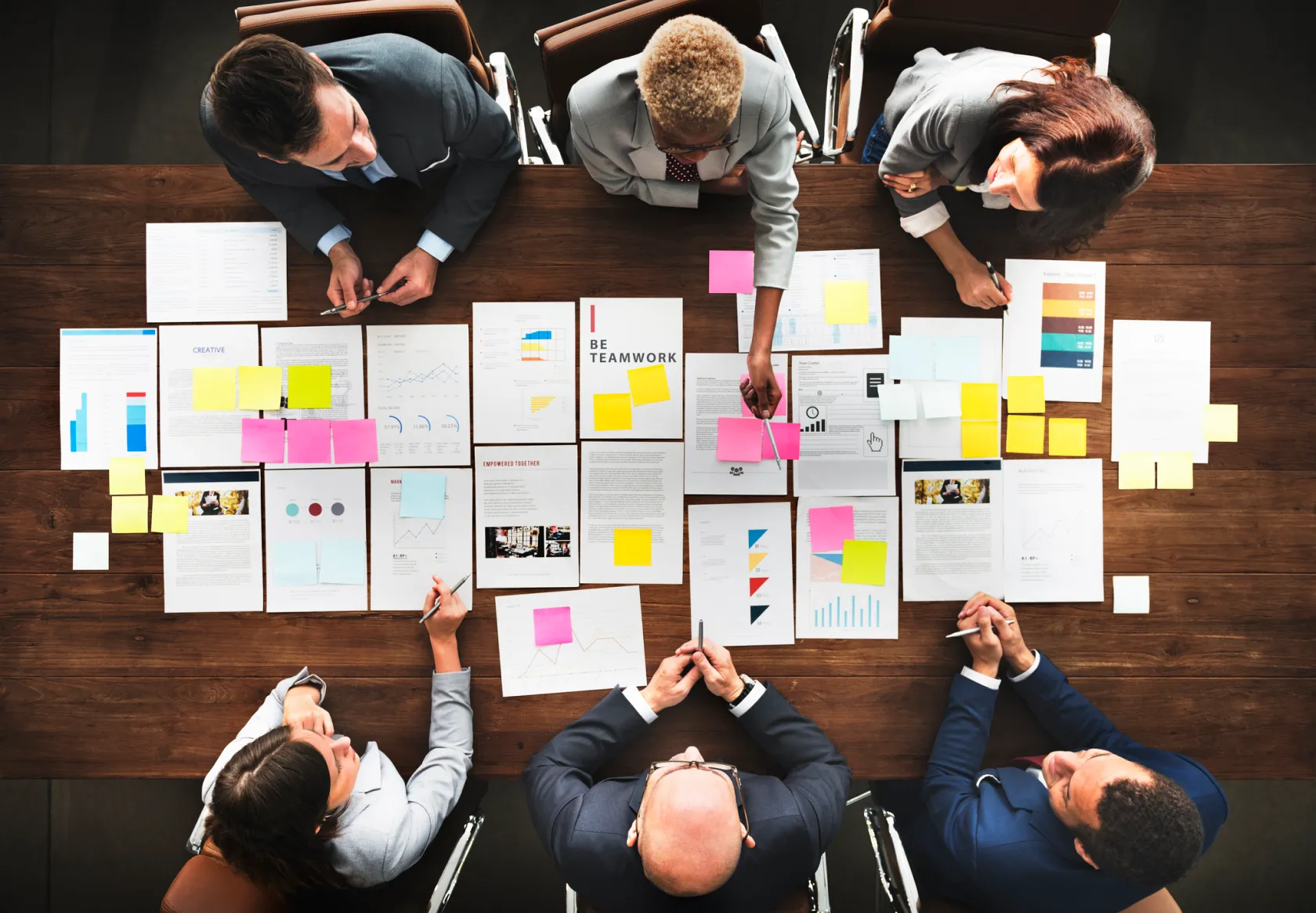 Birds eye view of a team gathered around a table with documents neatly laid out