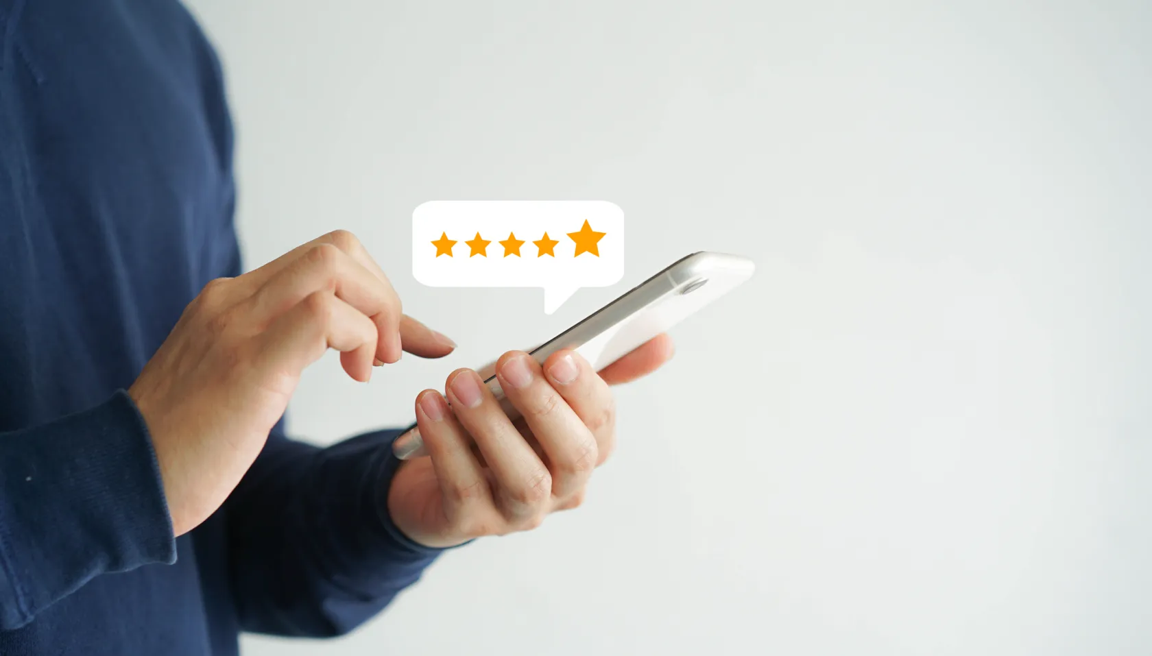 A person typing into a phone with an illustration of 5 star review popping out