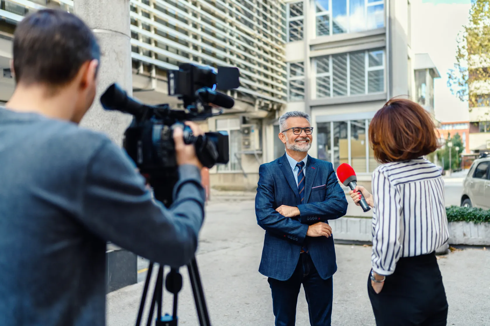 A businessman being interviewed by a news crew on a city street