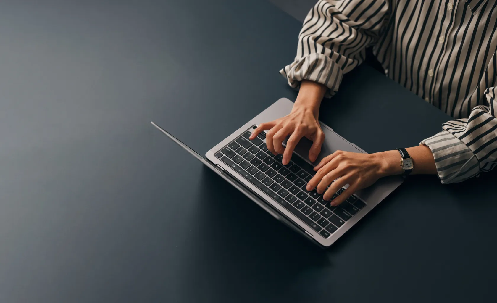 A person typing into a laptop at a table