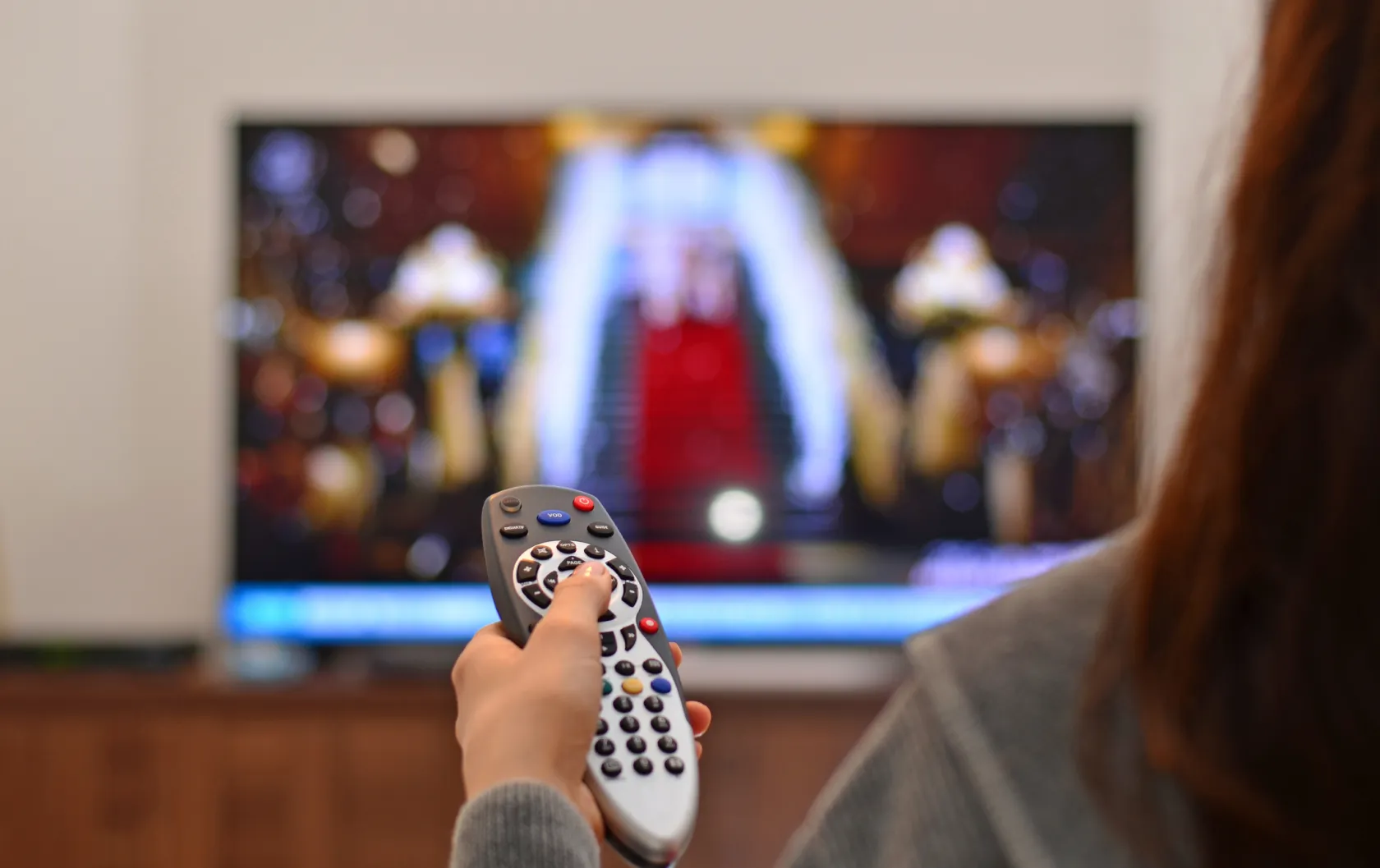 A person holding up a remote while watching TV