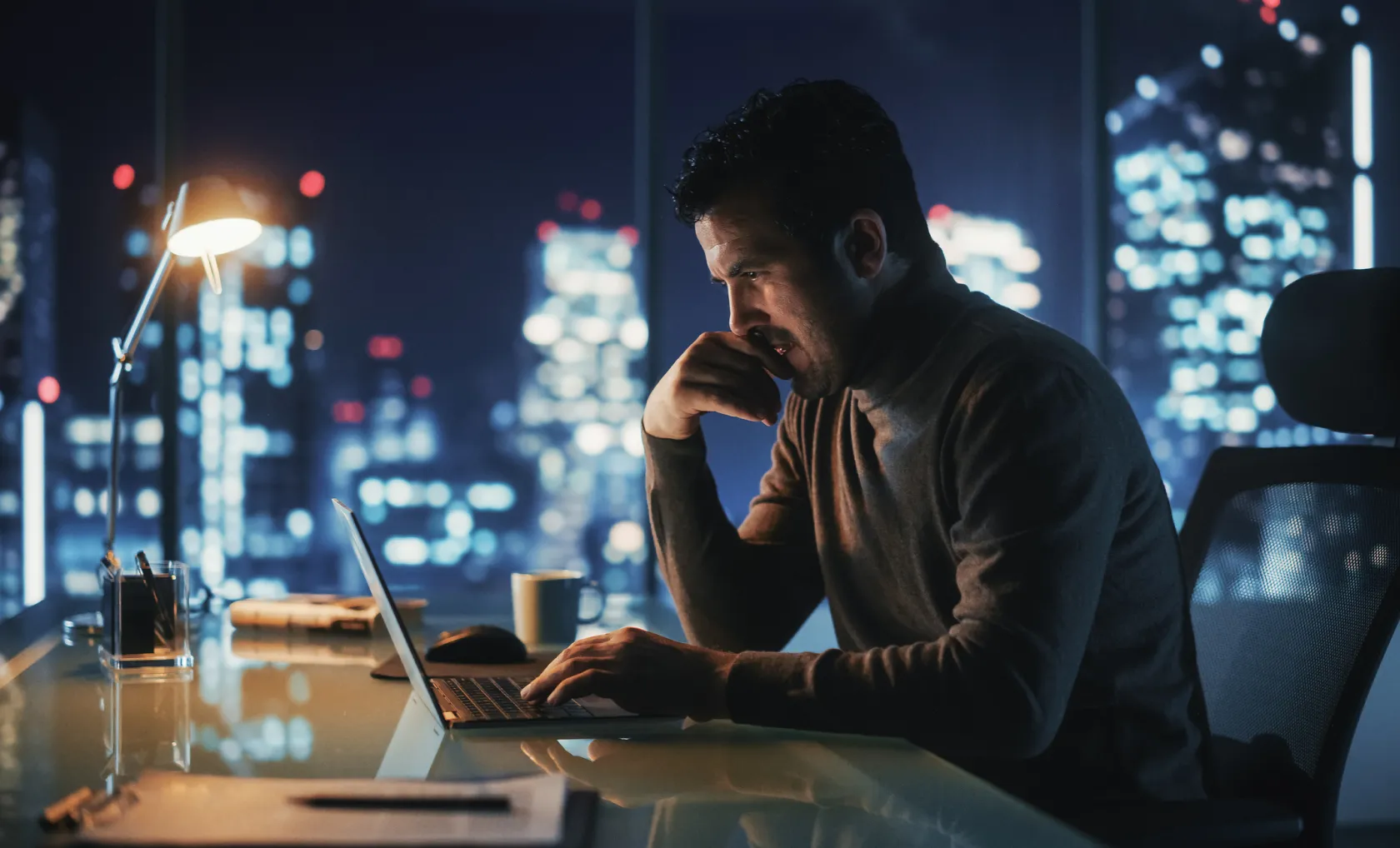 A man working on a laptop in an office late at night