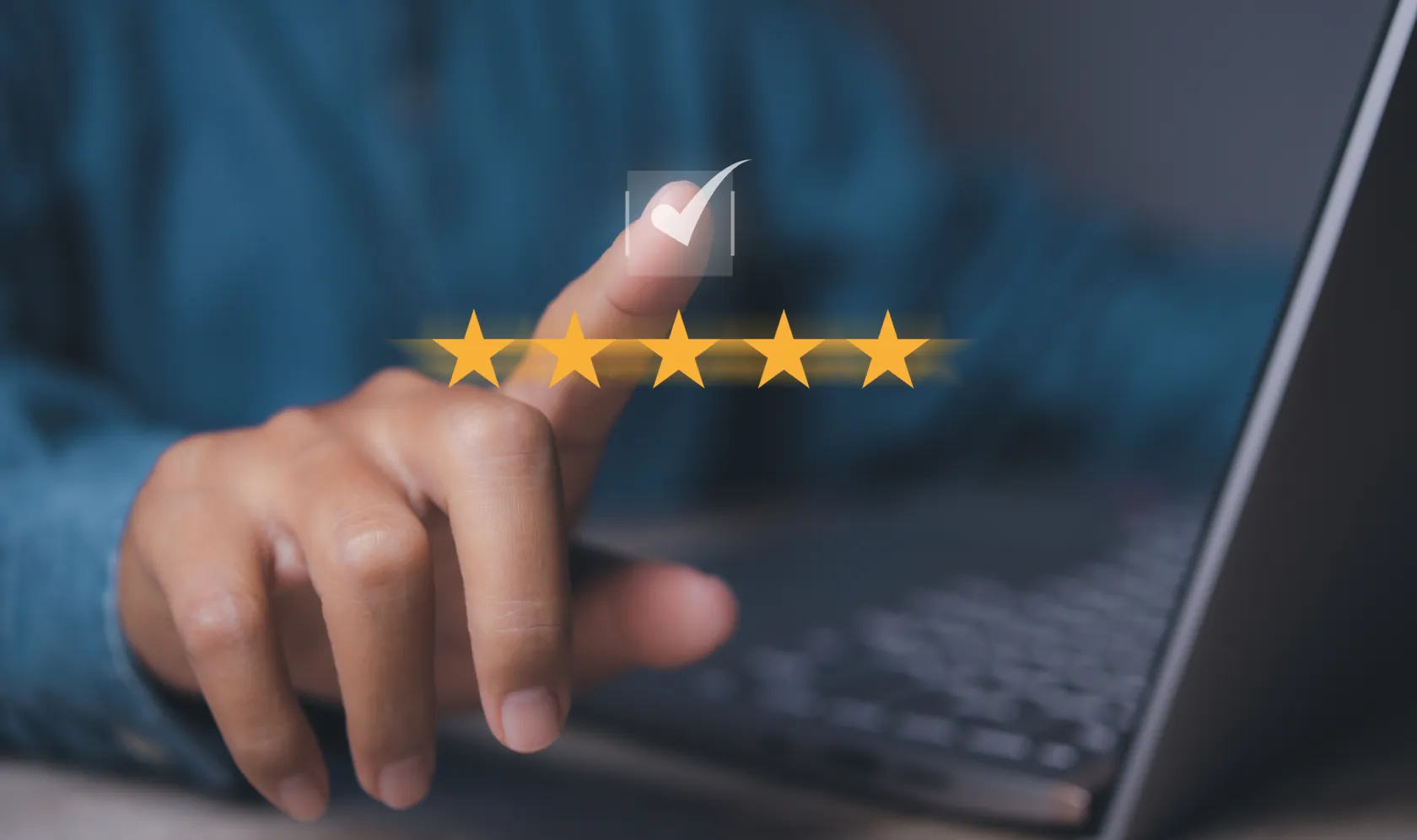 A person typing into a laptop with an illustration of a 5 star rating imposed over the image