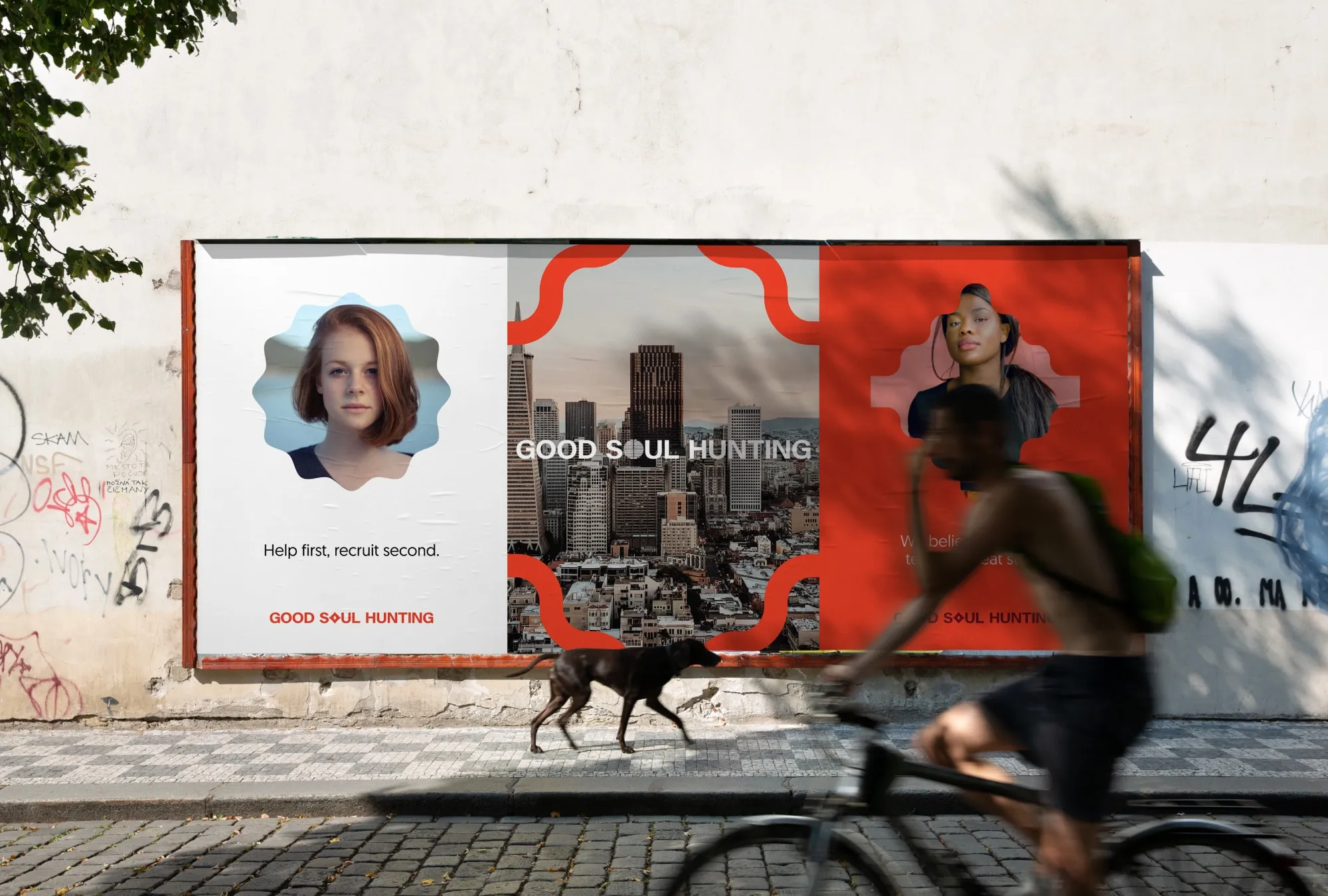Good Soul Hunting large format posters on outside wall with cyclist and dog passing by