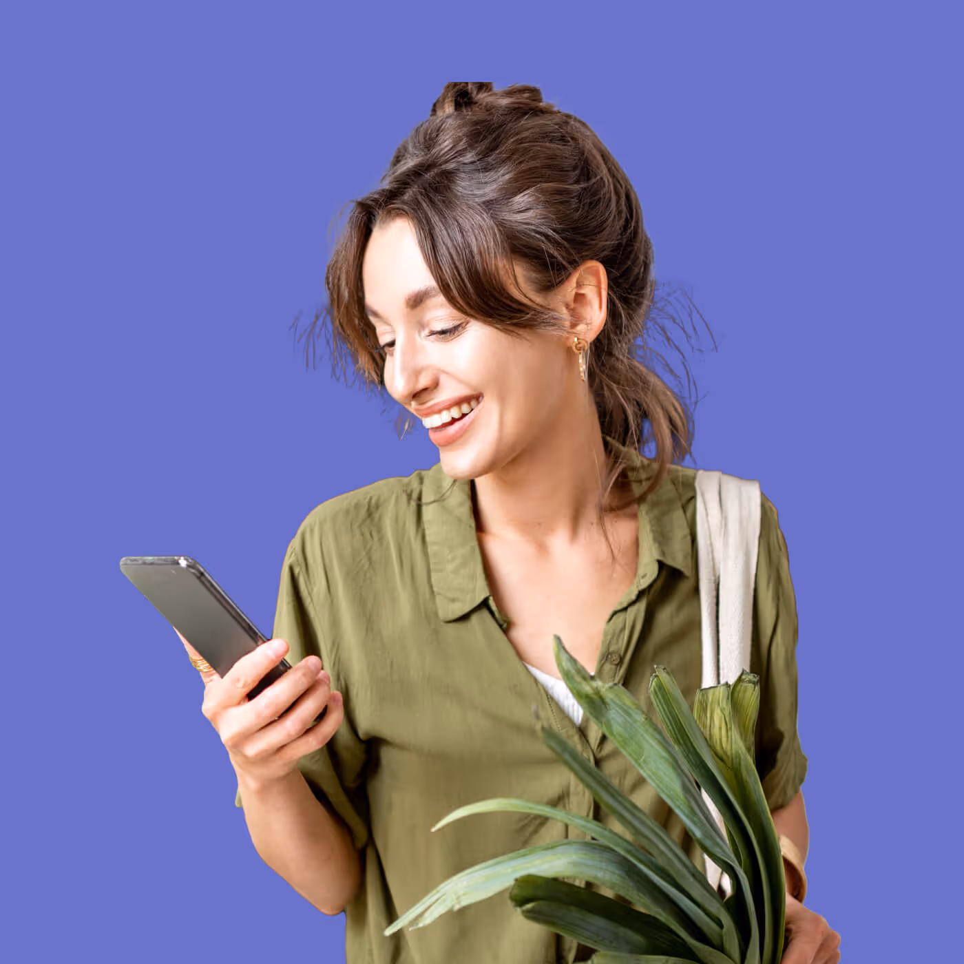 Woman in green shirt smiling while looking at smartphone against purple background