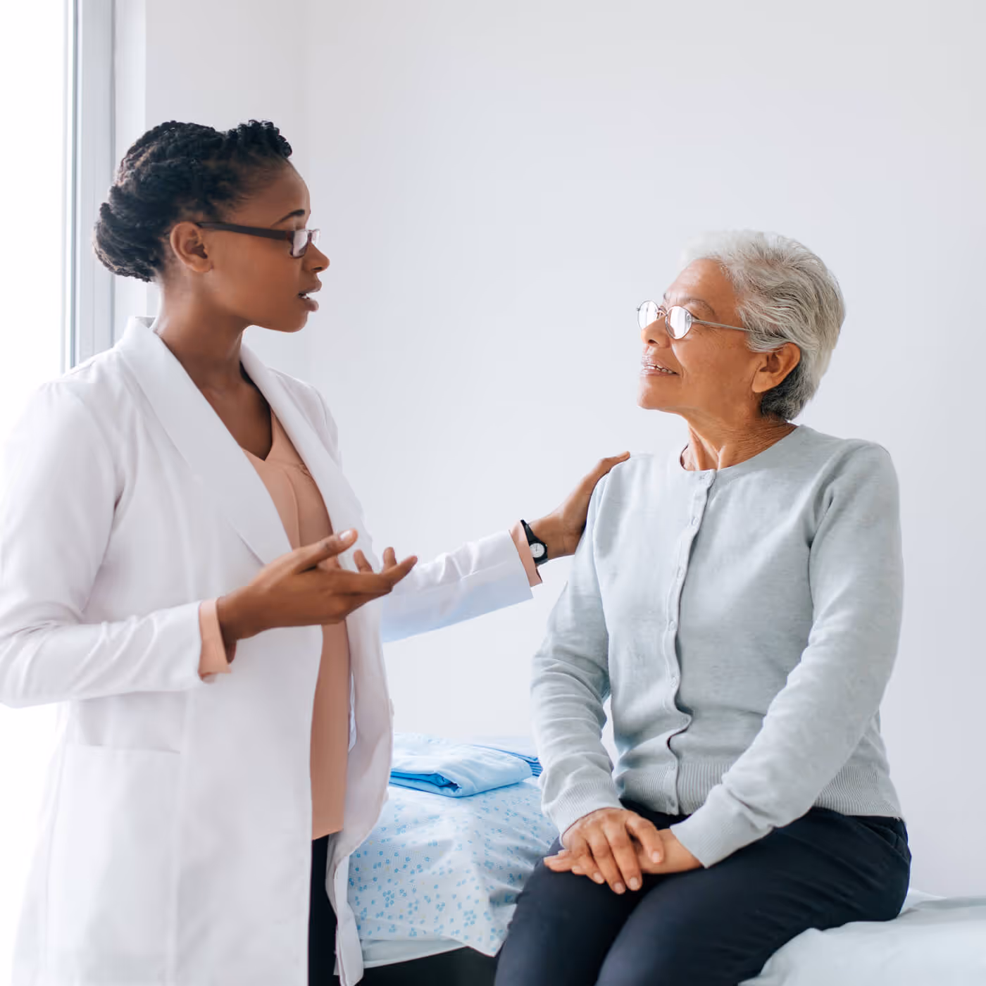 Healthcare provider in white coat consulting with older patient in clinical setting