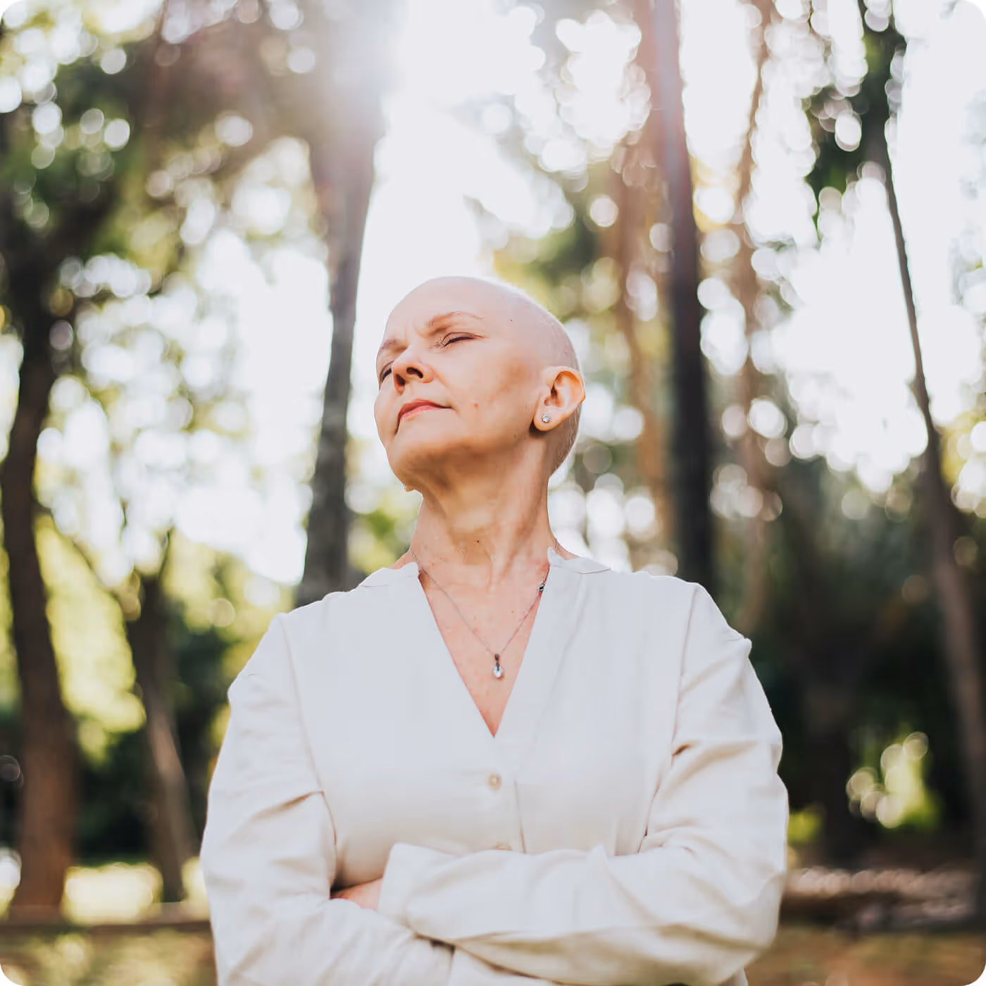 Woman with short hair in white blazer looking upward thoughtfully in natural outdoor setting with soft lighting and bokeh background