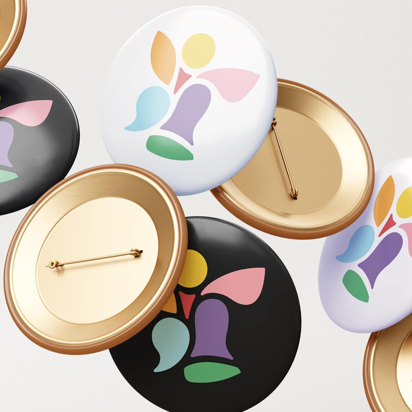 Collection of round pins showing a stylized multicolored abstract flower design on black and white backgrounds, with some pins showing their gold-colored backs.