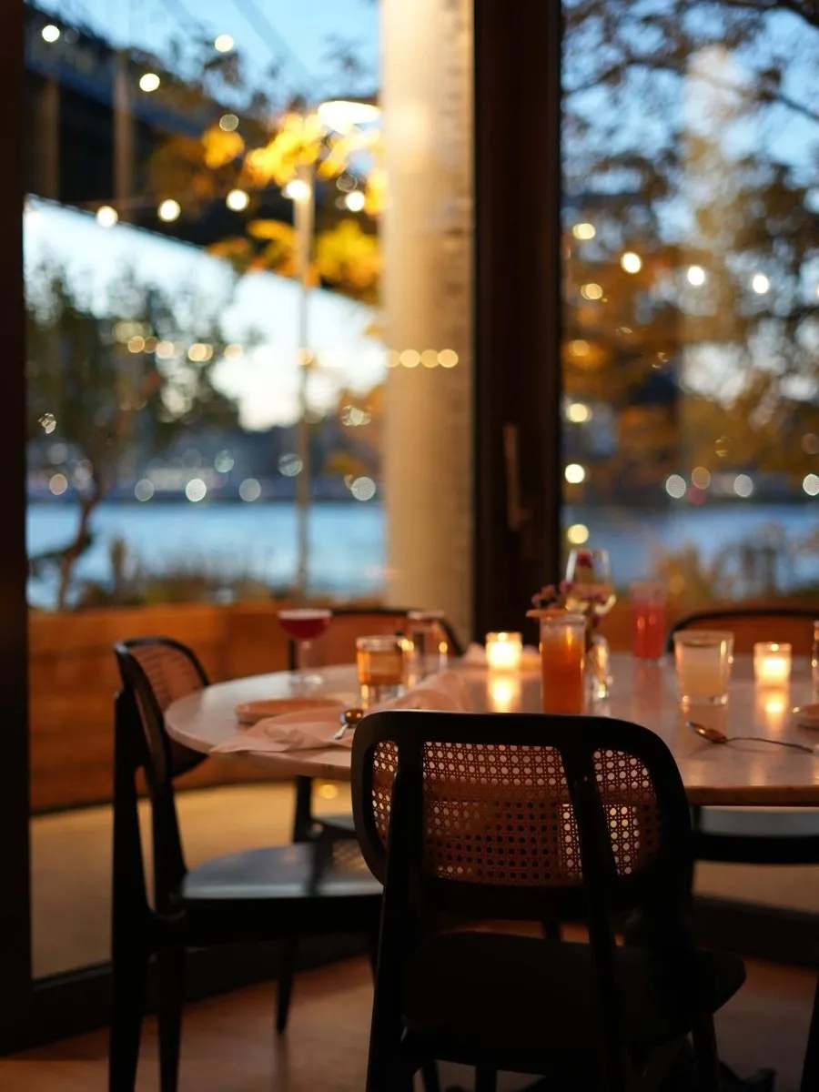 Celestine dining room at dusk, candlelit tables with a view of the Manhattan Bridge