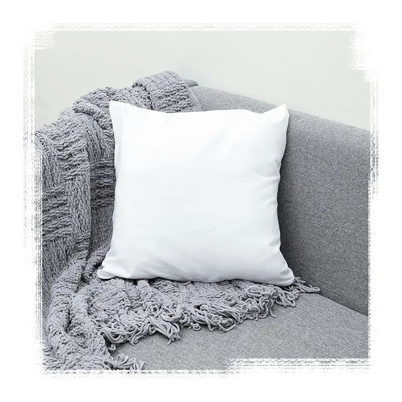 A white pillow and grey blanket on the corner of a modern, grey couch.