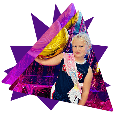 Young girl wearing a gymnastics outfit and a birthday sash holding a gold balloon against a shiny pink background.