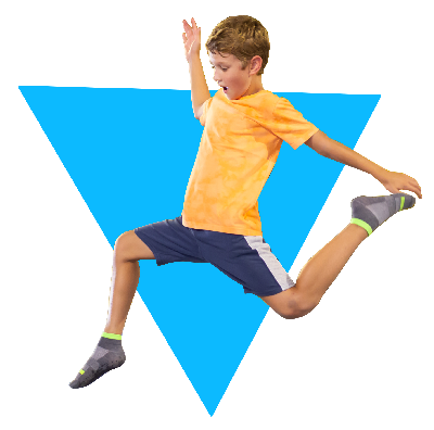 Young boy in an orange shirt and blue shorts jumping enthusiastically against a blue background.