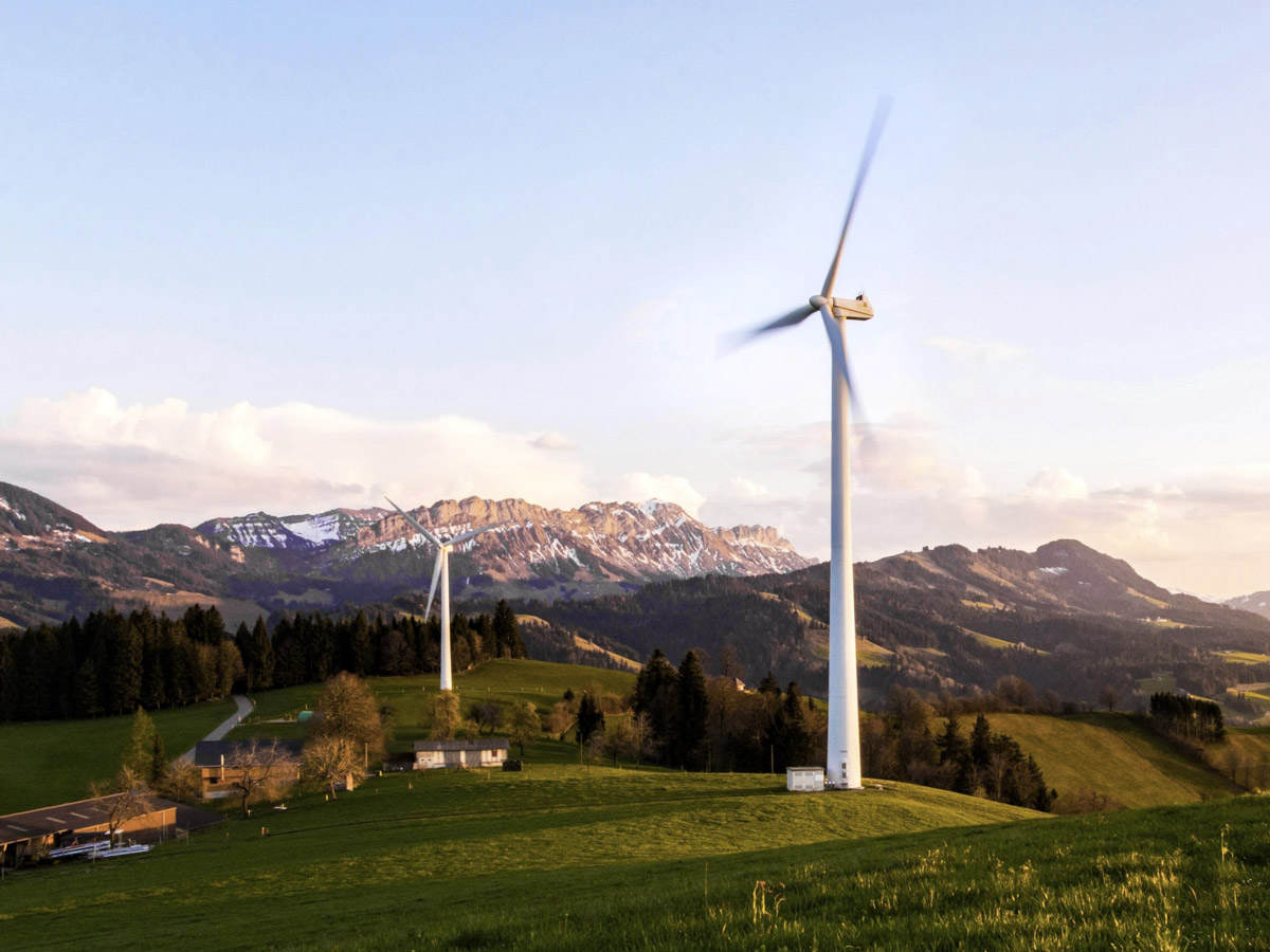Spinning wind turbine on a hill with a mountain scene in the background