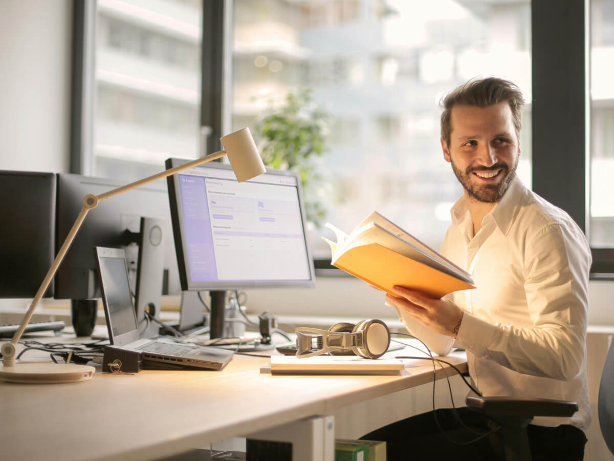 Man in office sitting at desk with computer and software on screen