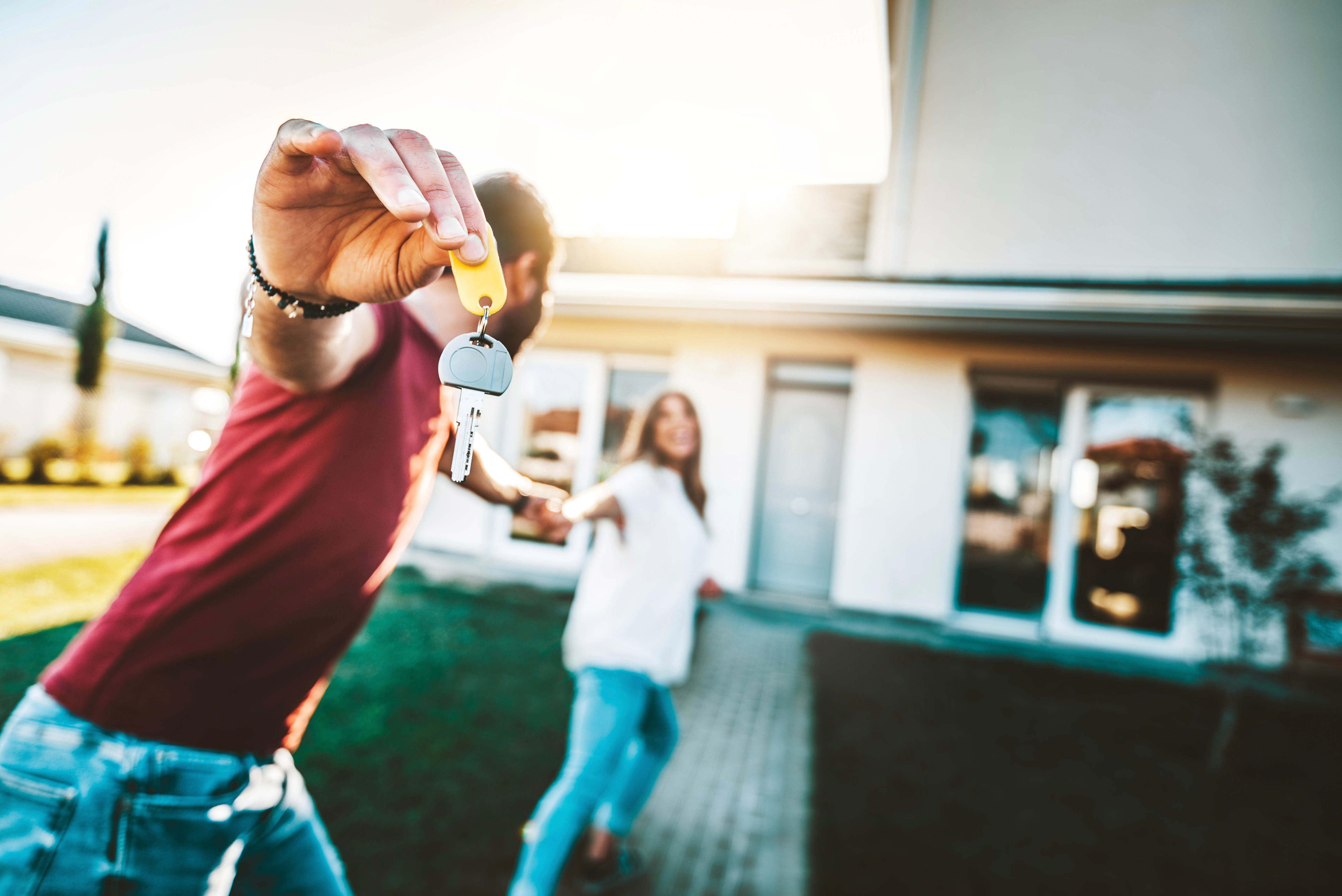 Happy couple holding house key in front of new home
