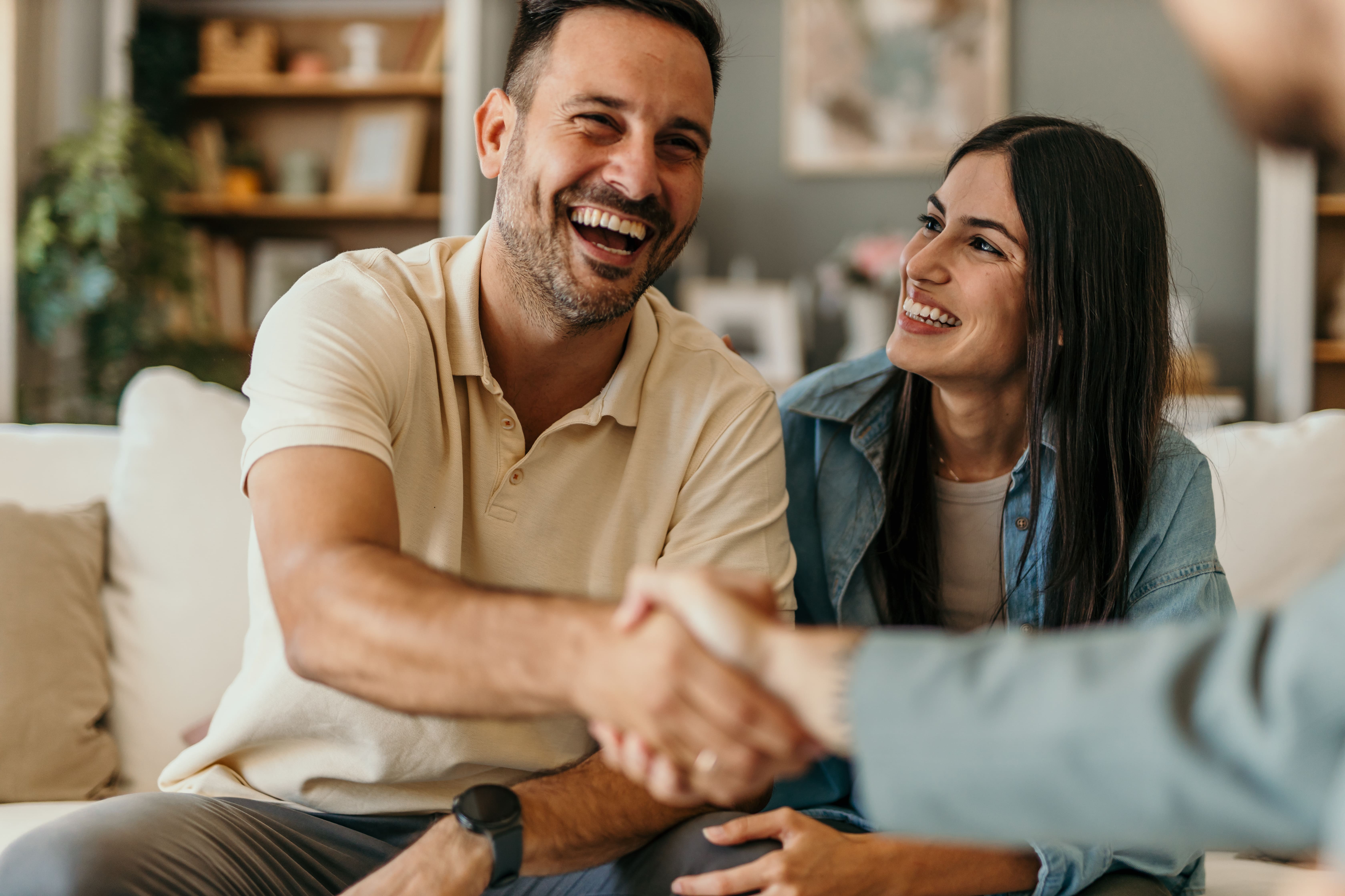 Happy couple shaking hands with an adviser