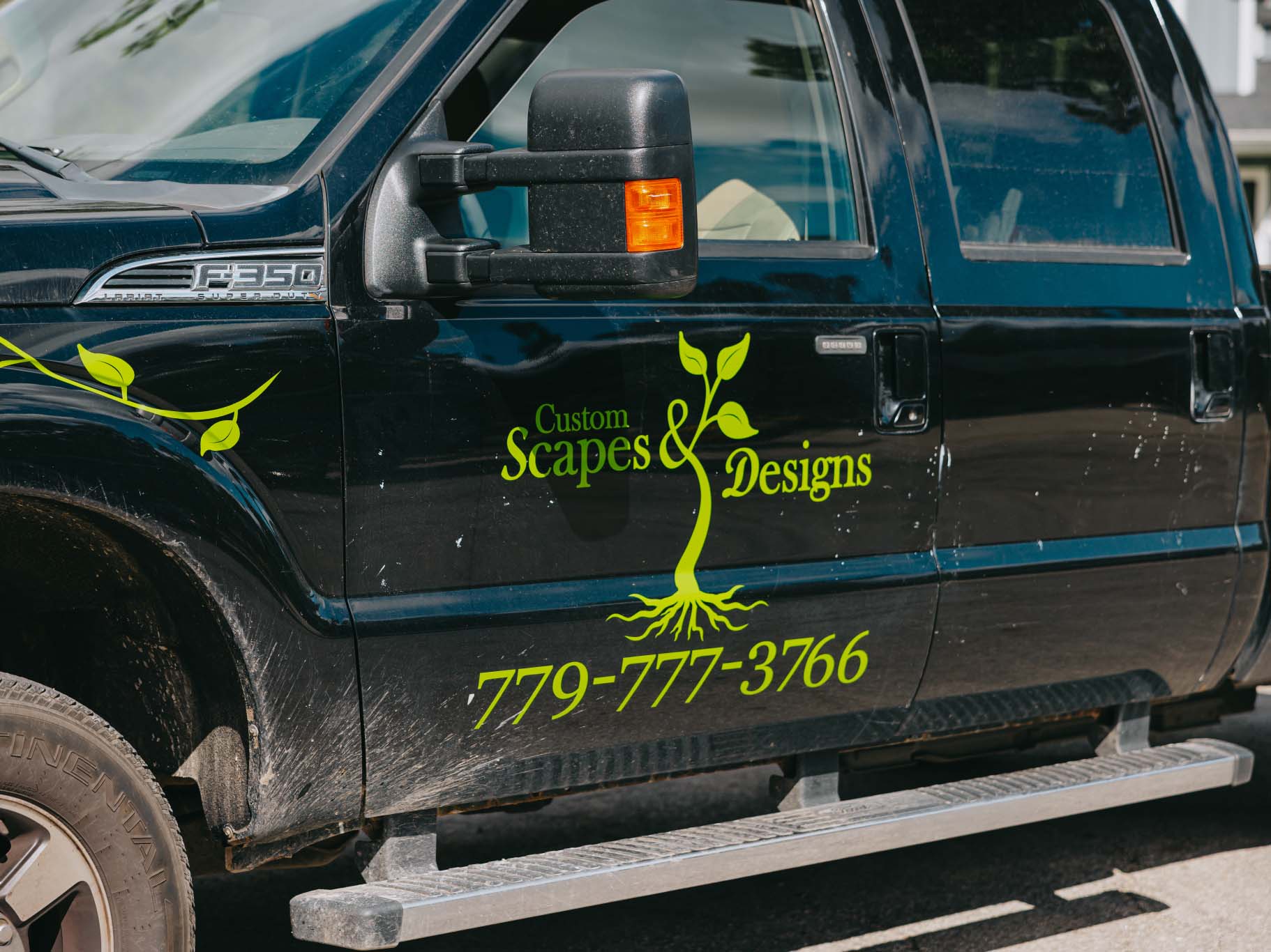 Custom Scapes and Designs work truck displaying company logo and phone number on job site
