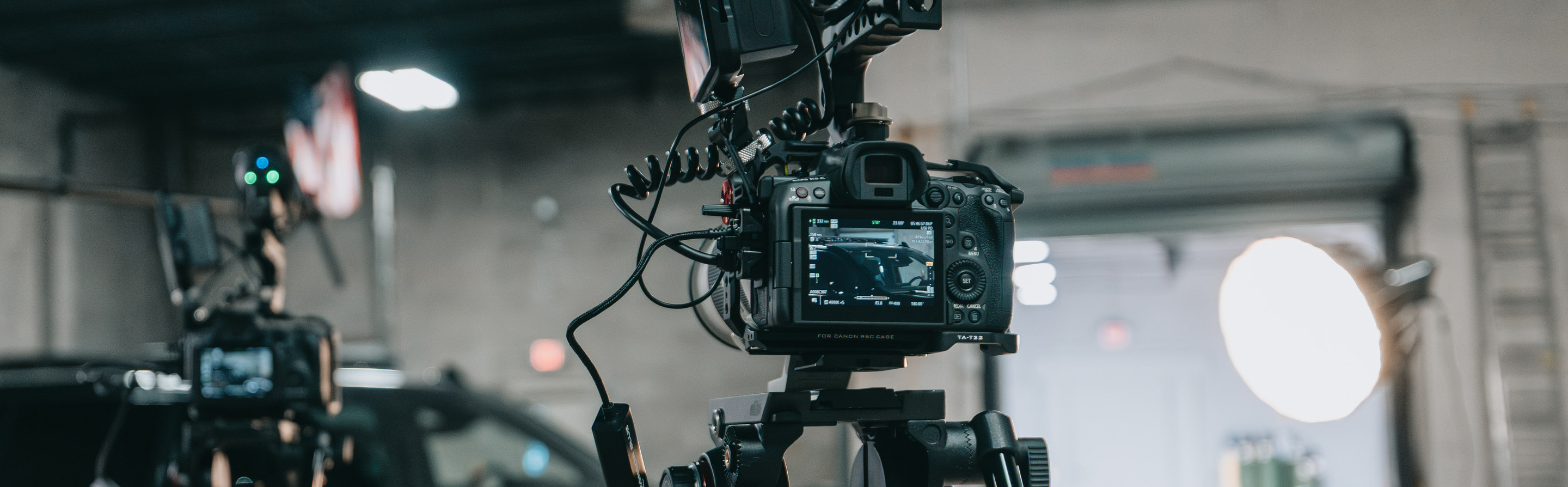 Canon cinema camera rig with a Rode microphone on a tripod during an Identity Start video shoot in a warehouse studio.