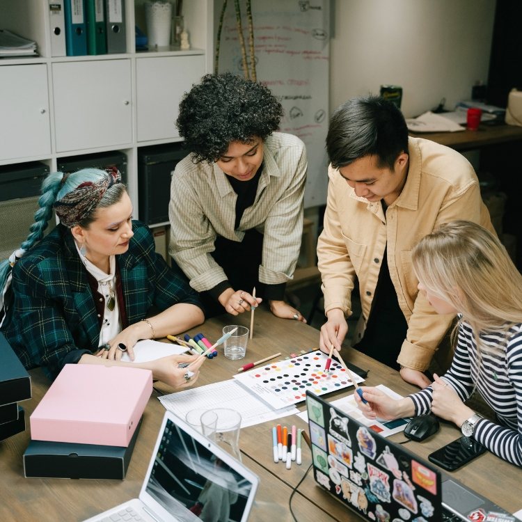 Team collaborating around a table with sketches and color swatches while planning an online store