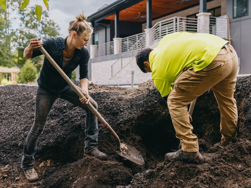 Custom Scapes & Designs crew digging a planting bed at a modern home