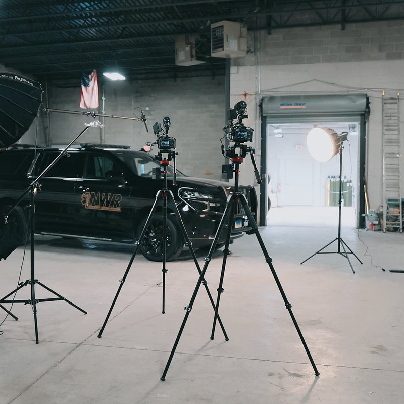 Full video set with lights and tripods around a Northwest Rescue SUV in a warehouse