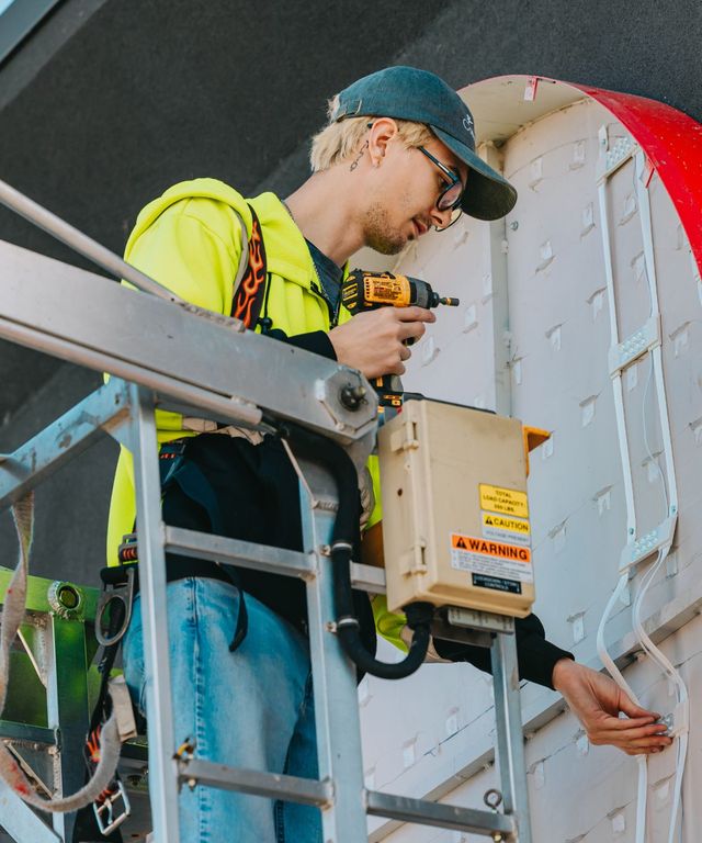 Sign technician using a cordless drill to install a sign