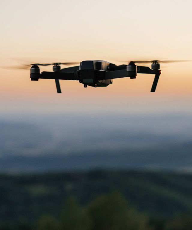 Drone hovering mid-air at sunset