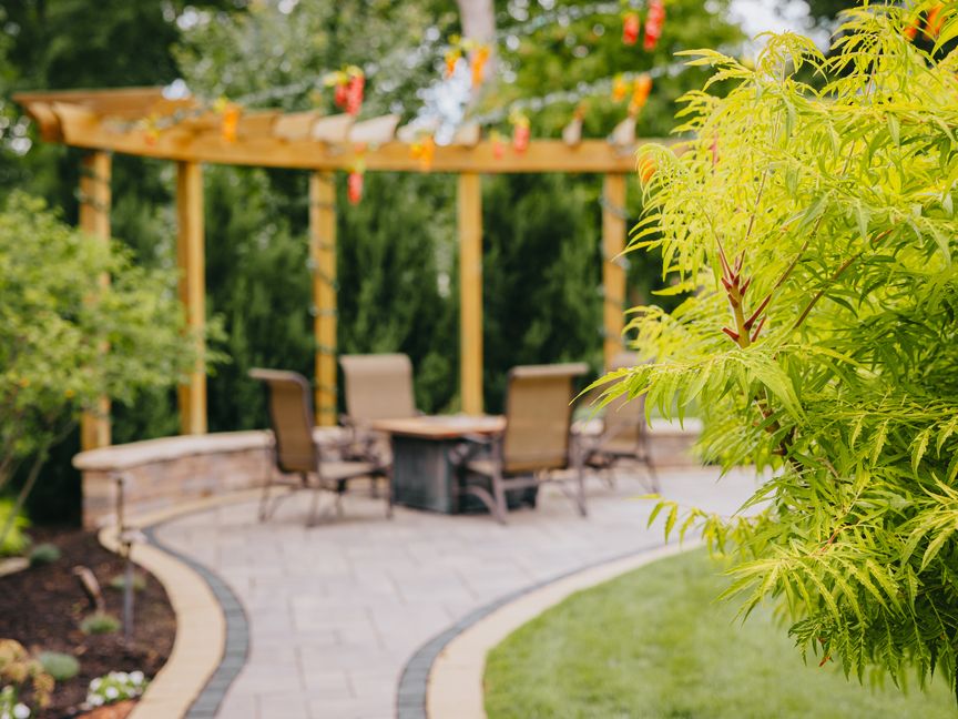 Paver patio with a wood pergola and outdoor seating built by Custom Scapes & Designs