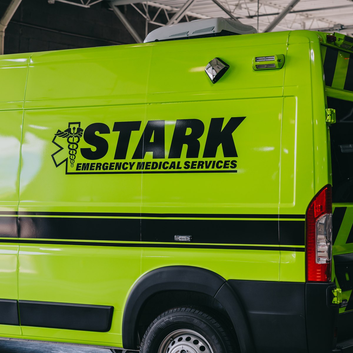 Rear doors of a lime green Stark County Ambulance unit with black reflective chevrons