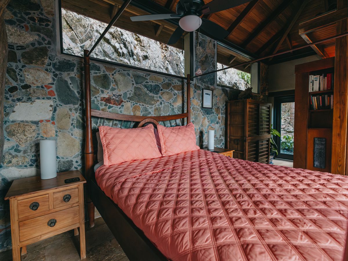 Moon Cottage bedroom with stone wall and a pink quilted bed