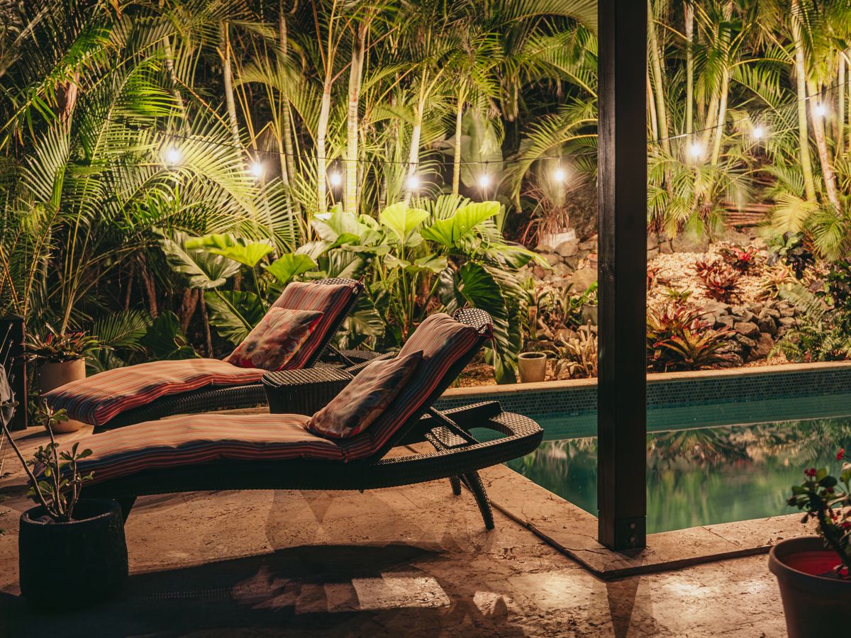Moon Cottage pool and lounge chairs lit at night among the palms